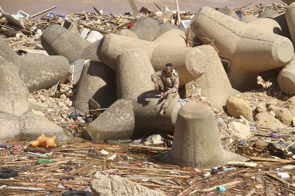 dpatopbilder - 13.09.2023, Libyen, Darna: Ein Mann sitzt auf einem Wellenbrecher und blickt auf einen Teil der Schäden nach den schweren Unwettern. In Libyen herrscht nach den furchtbaren Überschwemmu ...