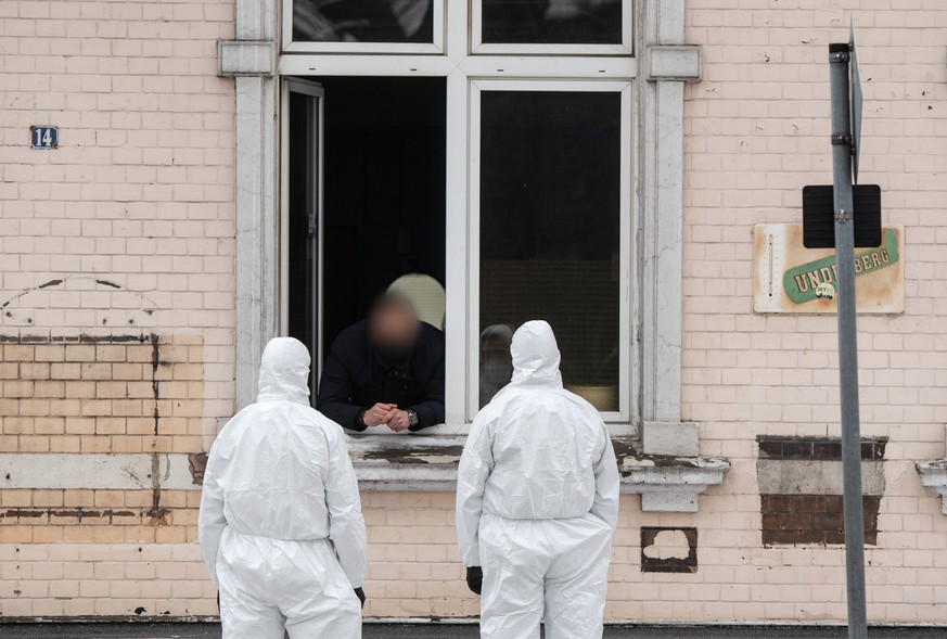 Einsatzkräfte der Polizei unterhalten sich durch ein Fenster mit einem Mann in Hamm.