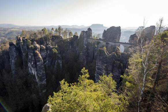 Touristen laufen über die Basteibrücke. Im Elbsandsteingebirge kann es ab Wochenmitte zu starken Sturmböen kommen.