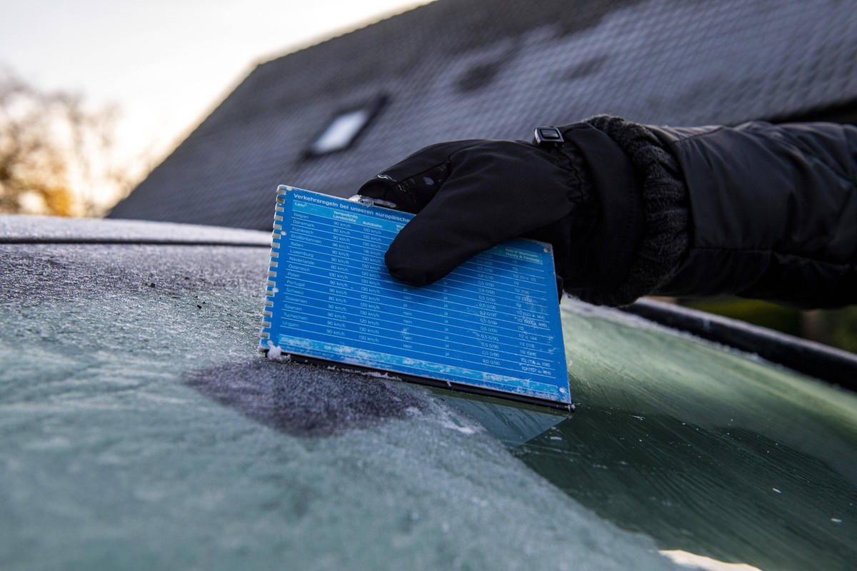 Wintereinbruch im Stra�enverkehr 25.11.2020 - Feature Verkehr, Winter, Wetter: Themenbild: Eine Hand kratzt das Eis von einer gefrorenen Autoscheibe, um die Windschutzscheibe an dem Fahrzeug eisfrei z ...