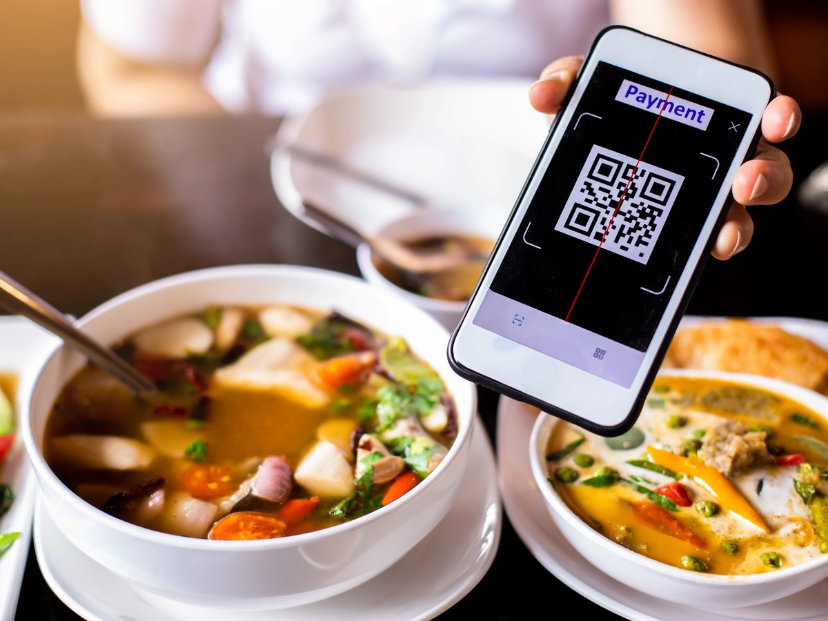 Customer hand using smart phone to scan QR code tag with blurry Thai food to accepted generate digital pay without money. Qr code payment concept.