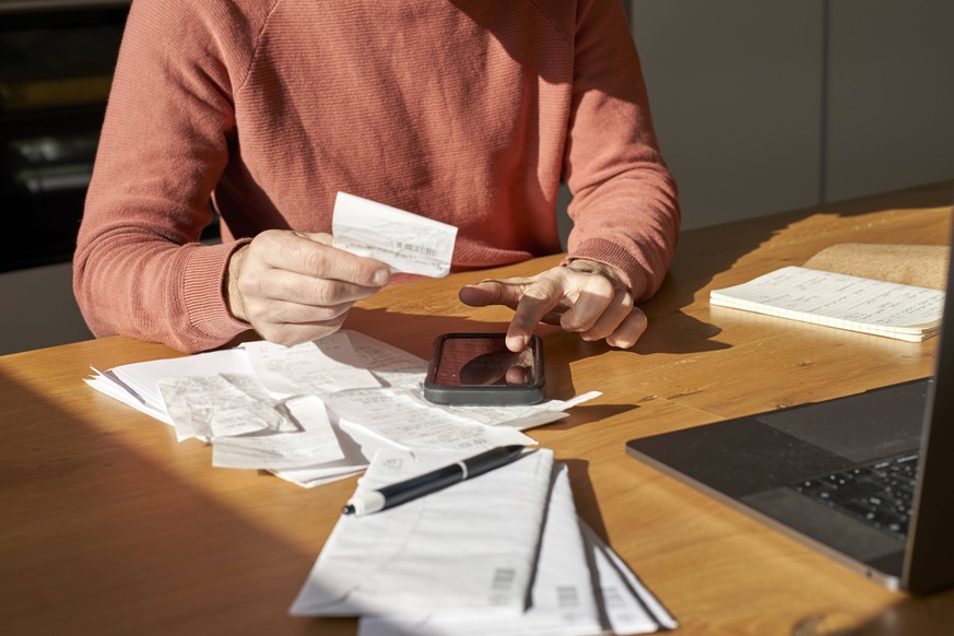 Hands of man with financial bills calculating on smart phone at desk model released, Symbolfoto property released, VEGF06180