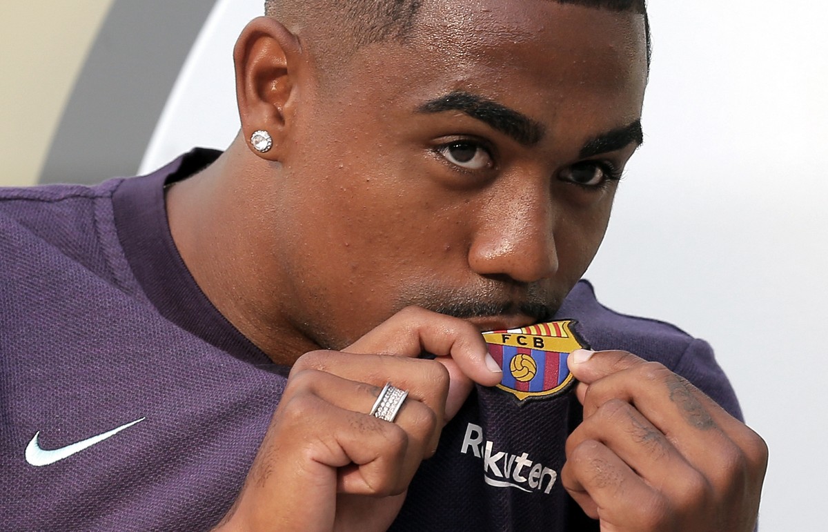 Brazilian soccer player Malcom Filipe Silva de Oliveira kisses the emblem on his shirt upon his arrival at the club's office at the Camp Nou stadium in Barcelona, Tuesday, July 24, 2018. Malcom h ...