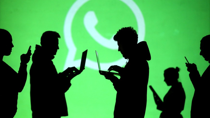 FILE PHOTO: Silhouettes of laptop and mobile device users are seen next to a screen projection of Whatsapp logo in this picture illustration taken March 28, 2018. REUTERS/Dado Ruvic/File Photo