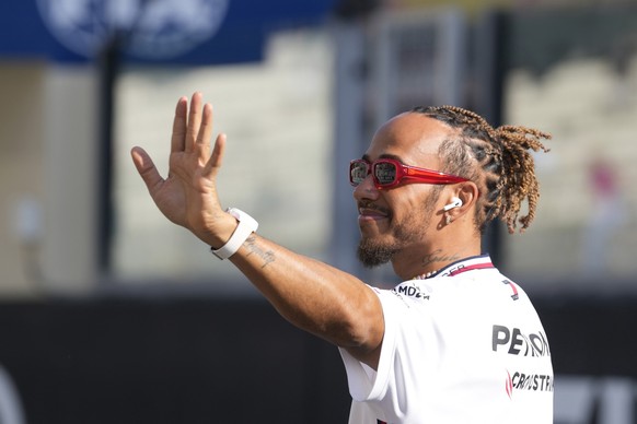 FILE - Mercedes driver Lewis Hamilton of Britain, waves as he arrives for the F1 drivers group picture ahead the drivers parade prior to the Abu Dhabi Formula One Grand Prix at the Yas Marina racetrac ...