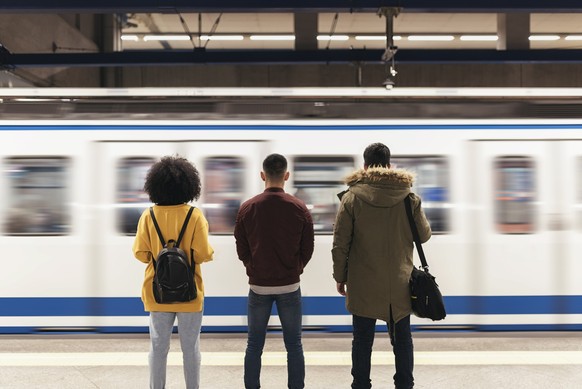 Group of friends waiting the train in the platform of subway station. Public transport concept.