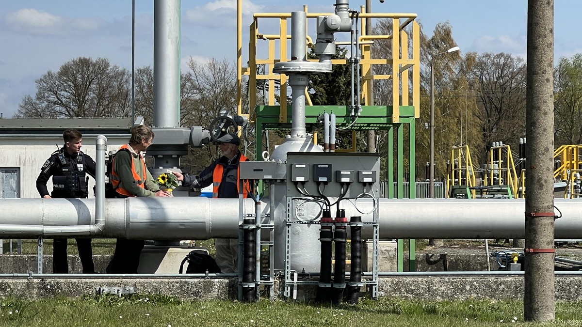 Aktivisten stehen in der Pumpstation neben einem Polizisten. Bei einer Protestaktionen der Gruppe &quot;Letzte Generation&quot; gegen Ölimporte haben Klimaschützer versucht, die Versorgung über die Ro ...