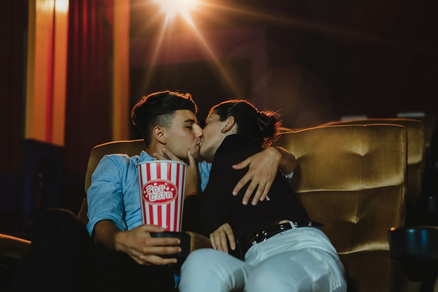 Romantic loving couple at the cinema, Portrait of young couple kissing and enjoying the movie during a date at the cinema theater.