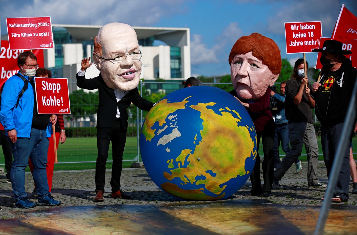 Demonstrators wearing masks depicting German Minister of Economic Affairs and Energy Peter Altmaier and Chancellor Angela Merkel hold an earth globe as activists protest for a faster coal exit in fron ...