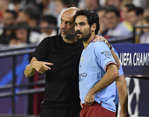 Manchester City&#039;s Ilkay Gundogan stands on the touchline with Manchester City&#039;s head coach Pep Guardiola during the group G Champions League soccer match between Sevilla and Manchester City  ...