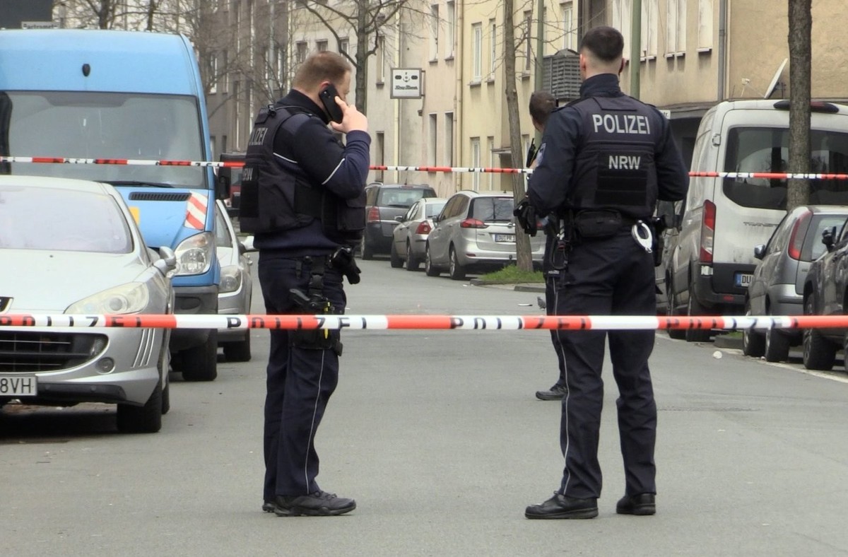 28.02.2024, Nordrhein-Westfalen, Duisburg: Zwei Beamte stehen an einem abgesperrten Tatort. In Duisburg sind zwei Kinder schwer verletzt worden. «Wir gehen von einer Straftat aus», sagte eine Polizeis ...