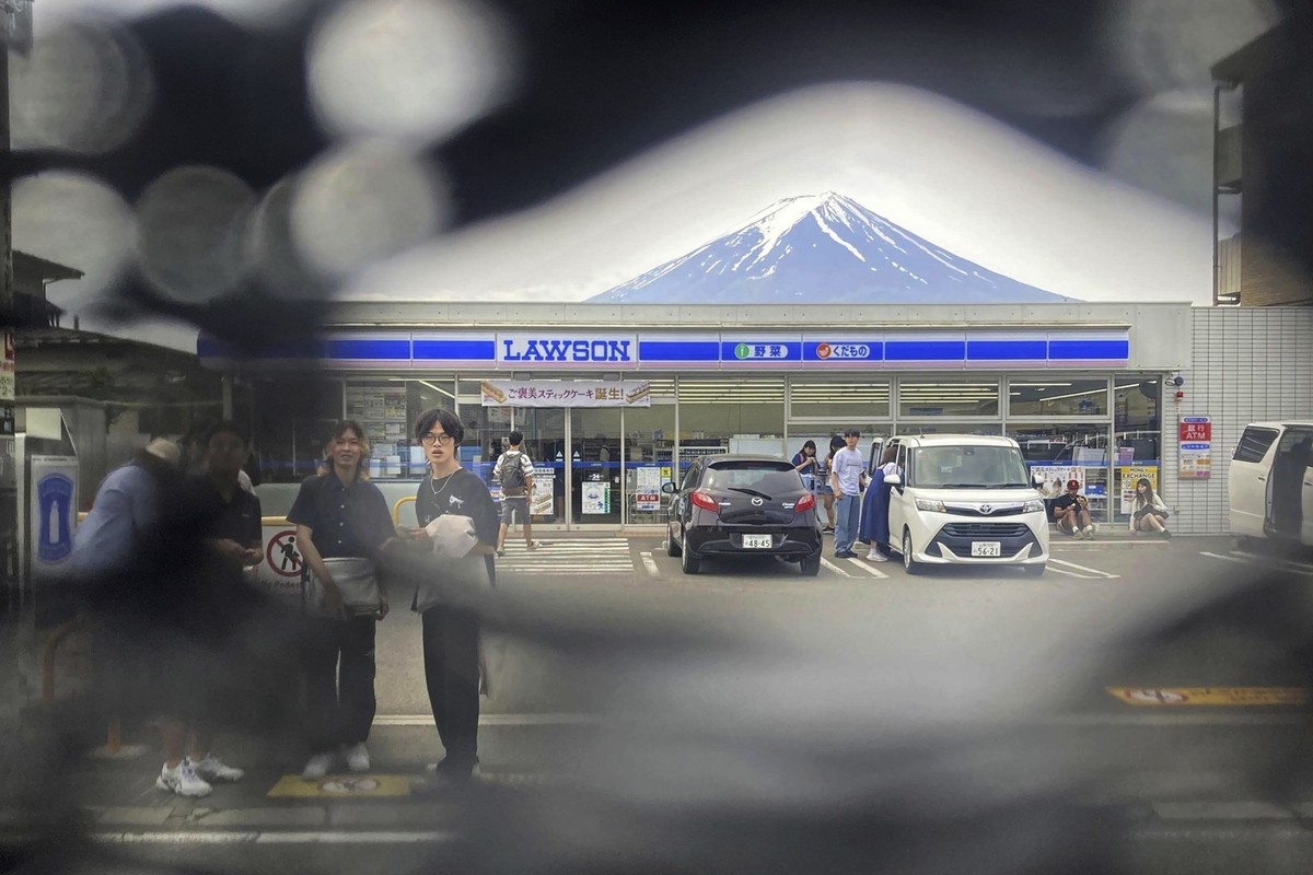 Mt. Fuji is seen through a hole on a black screen installed across from a convenience store in Fujikawaguchiko town, Yamanashi prefecture, central Japan on May 24, 2024. The town that erected the huge ...
