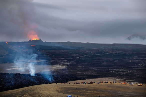 21.07.2023, Island, Fagradalsfjall: Lava tritt aus dem Krater eines Vulkans in der Nähe des Berges Litli-Hrútur aus, etwa 40 Kilometer südwestlich von Reykjavik. Im Vordergrund stehen «Vulkan-Touriste ...