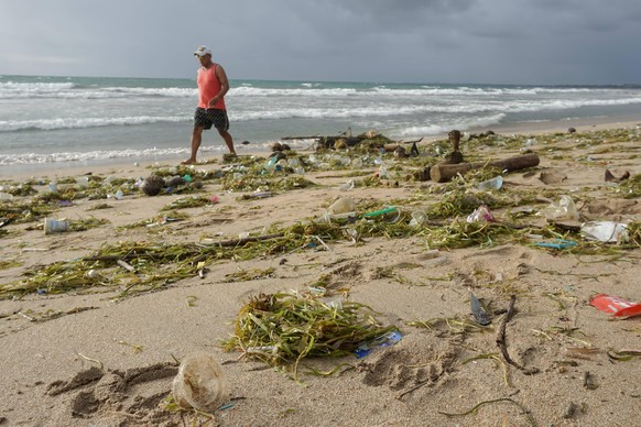 December 20, 2020, Badung, Bali, Indonesia: A man walks along the beach among the trashes..Tons of Trash reportedly dumped in the rivers by the citizens, and carried onto the beach during the rainy se ...