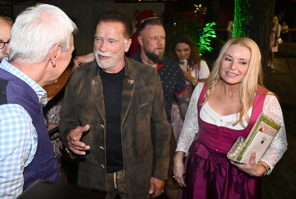 21.09.2023, Bayern, M�nchen: Der Wirt des Marstallzelts Siegfried Able (l-r) der Schauspieler Arnold Schwarzenegger und seine Freundin Heather Milligan gehen aus dem Marstallzelt. Die 188. Wiesn finde ...