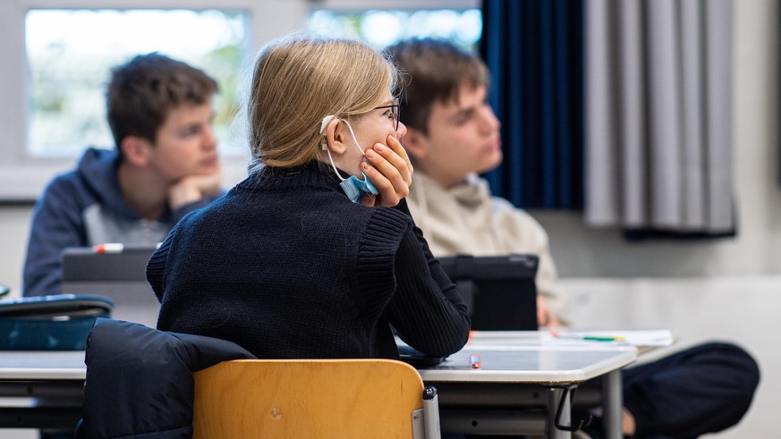 In der 9. Klasse der Gesamtschule in Münster hat eine Schülerin ihre Maske unter das Kinn gezogen. Seit dem 02.11.2021 fällt die Maskenpflicht in Schulen am Sitzplatz im Klassenzimmer weg. Schülerinne ...