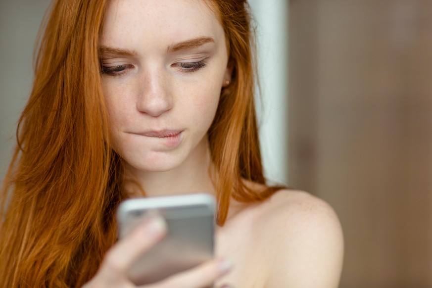 Closeup portrait of a beautiful redhead woman using smartphone