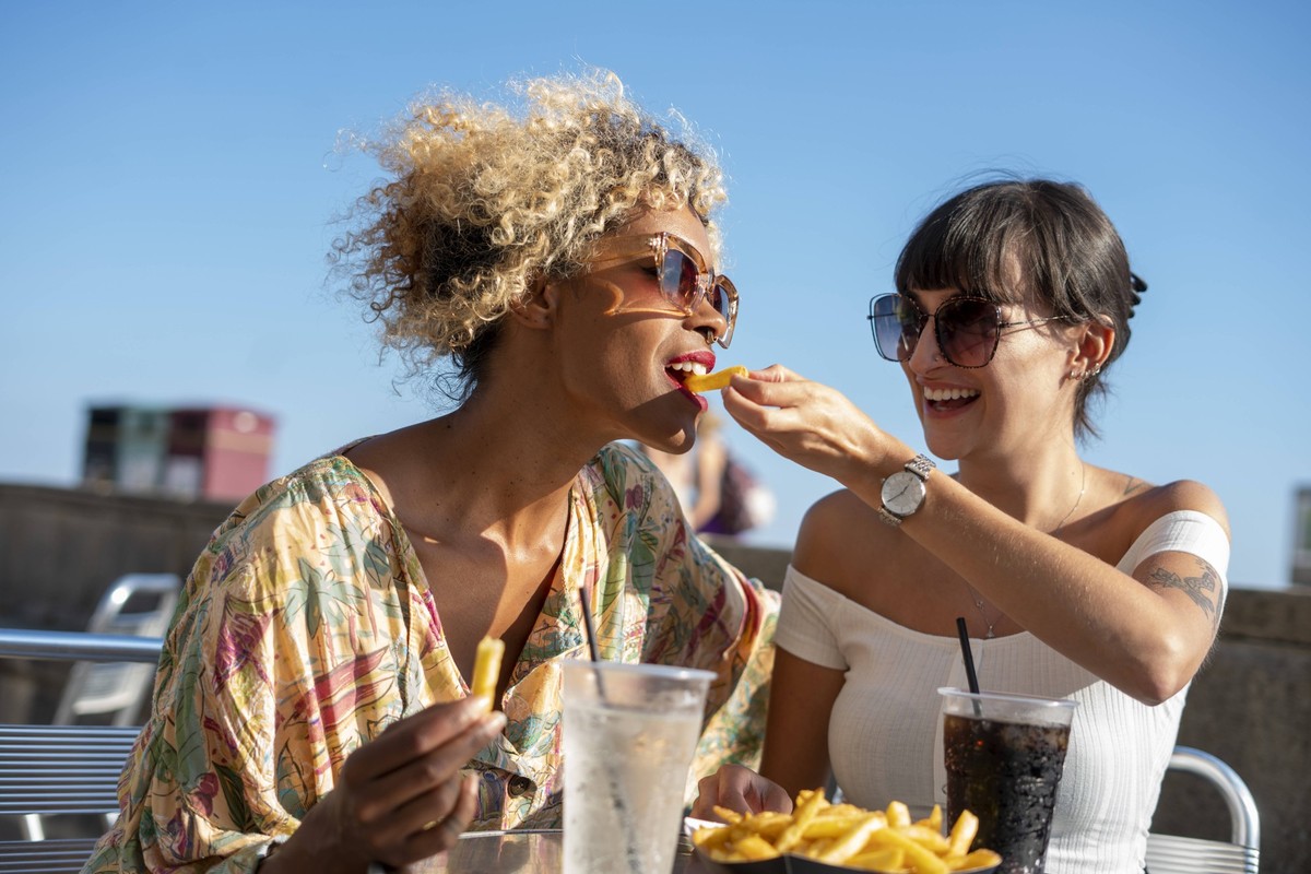 Female couple eating french fries in outdoor restaurant model released Copyright: xCulturaxCreativex