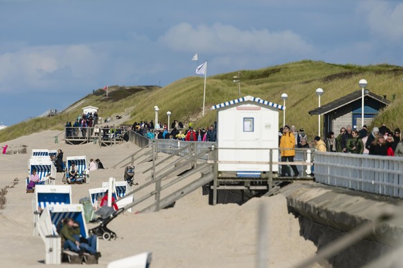 05.10.2019, Schleswig-Holstein, Westerland: Menschen gehen bei strahlendem Sonnenschein auf der Promenade am Strand entlang. Foto: Frank Molter/dpa | Verwendung weltweit