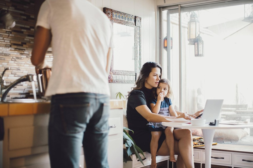 Mother working on laptop while daughter looking at father standing in kitchen , model released, property released Copyright: xMaskotx , MA76674