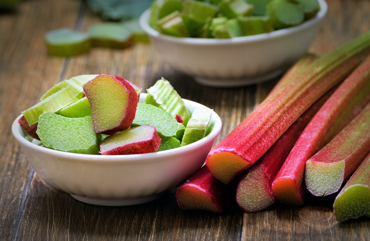 Fresh rhubarb in white bowl on wooden table