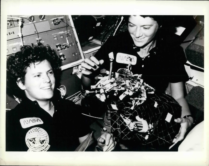 1984 - Bag Of Worms: Dr. Kathryn D. Sullivan, left and Sally Ride show off what appears to be a bag of worms a product of their creativity. The bag is a sleep restraint and the majority of the worm ar ...