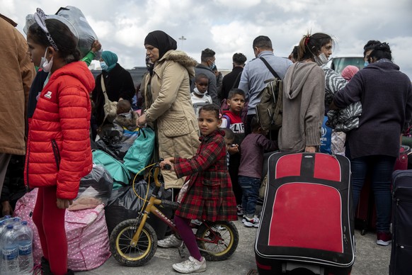 FILE - In this Sunday, Nov. 1, 2020 file photo, migrants from camps from the eastern Aegean islands wait to board on buses after their disembarkation from a ship, at the port of Lavrio, south of Athen ...