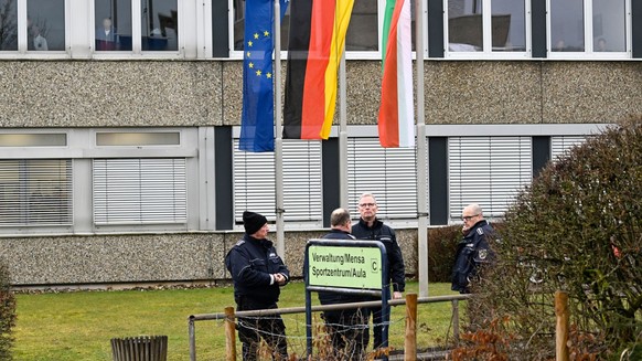 13.03.2023, Nordrhein-Westfalen, Freudenberg: Mitarbeiter des Ordnungsamtes stehen vor dem Schulzentrum des ermordeten Mädchens. Die Schule hat geöffnet, die Fahnen sind auf Halbmast geflaggt und die  ...