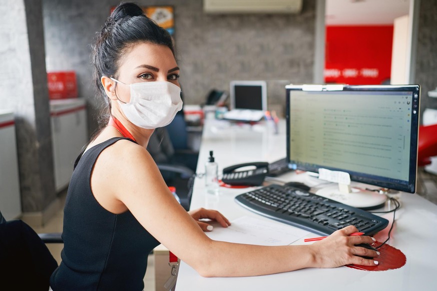 Businesspeople wearing masks in the office and working on bigger distance for safety during COVID-19 pandemic