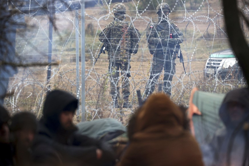 Polish border guards stand near the barbed wire as migrants from the Middle East and elsewhere gather at the Belarus-Poland border near Grodno, Belarus, Wednesday, Nov. 10, 2021. The German government ...