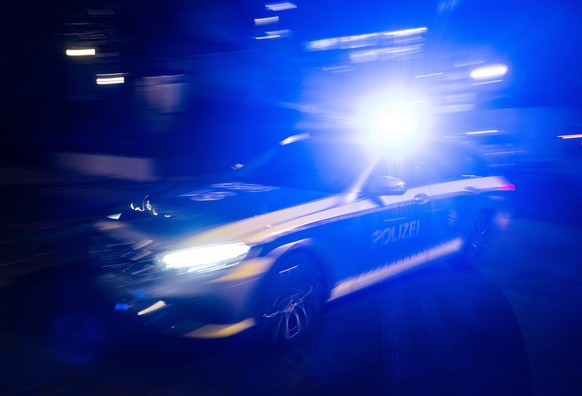 ILLUSTRATION - 30.11.2023, Baden-Württemberg, Stuttgart: Ein Polizeifahrzeug fährt mit Blaulicht an einem Gebäude vorbei. (zu dpa: «Polizei fahndet mit Hubschrauber nach Autofahrer») Foto: Marijan Mur ...