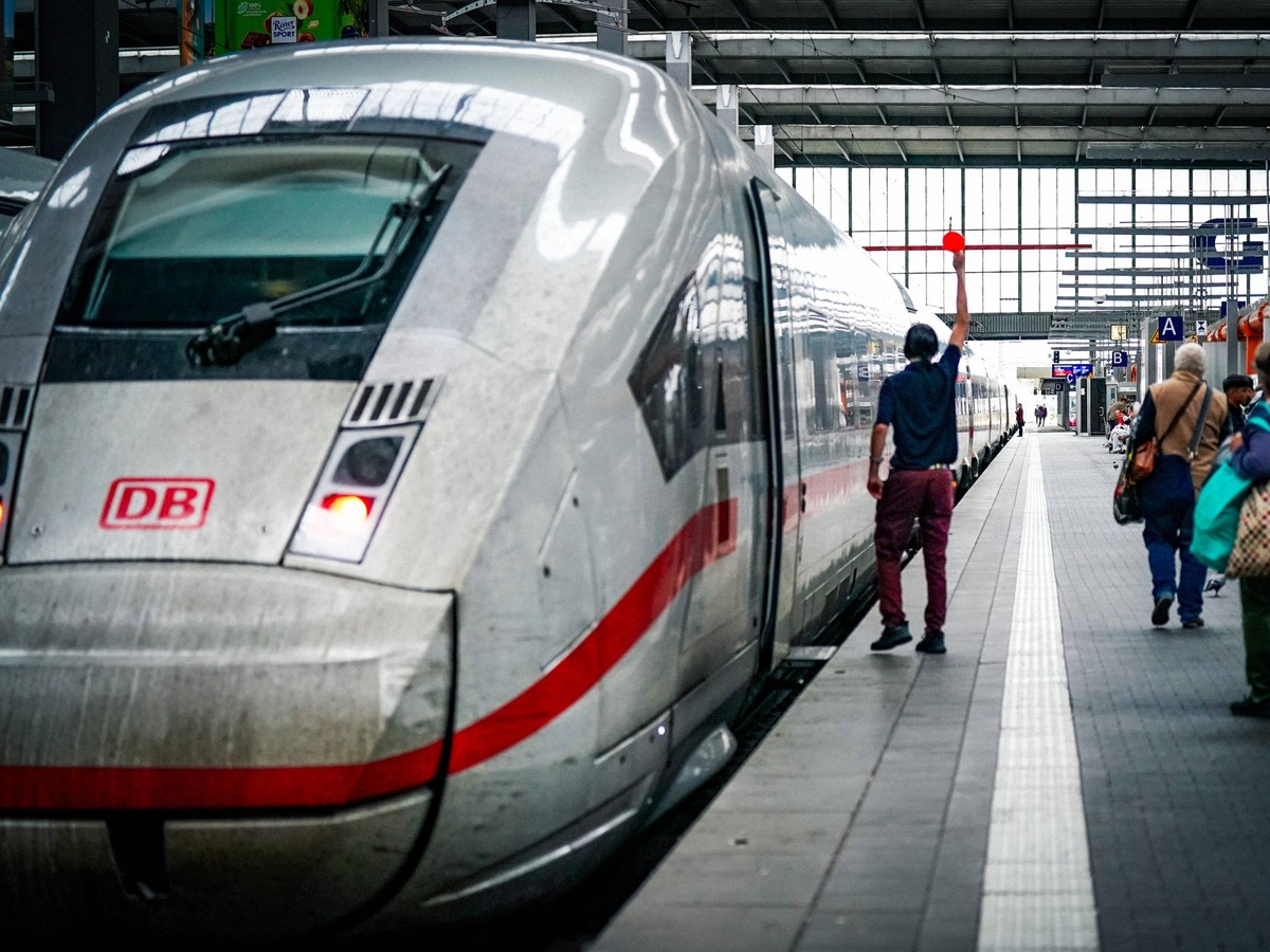 Deutschland, Europa, moderner ICE-Hochgeschwindigkeitszug der Deutschen Bahn im Hauptbahnhof, Bahnsteig voller Reisender, ein Zugbegleiter mit erhobenem Signalstab koordiniert die Abfahrt, lebendiger ...