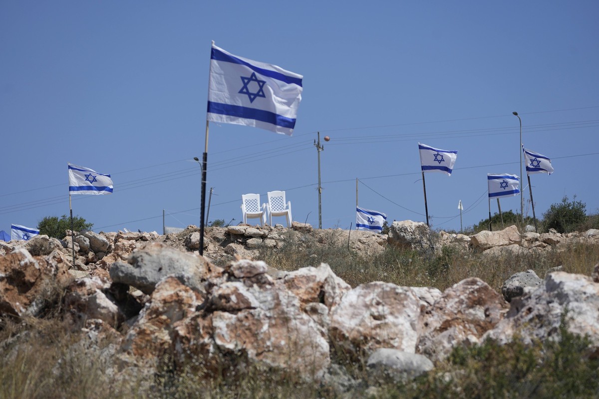 ARCHIV - 23.05.2025, Palästinensische Gebiete, Bruqin: Israelische Flaggen flattern auf einem Hügel, der an palästinensische Grundstücke angrenzt, die über Nacht von israelischen Siedlern angegriffen  ...