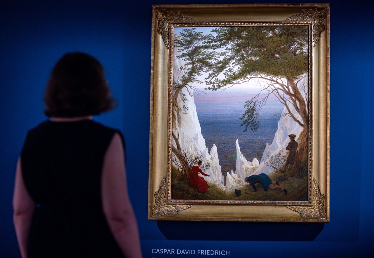 15.08.2024, Mecklenburg-Vorpommern, Greifswald: Eine Museumsmitarbeiterin steht vor dem Gemälde &quot;Kreidefelsen auf Rügen&quot; (um 1818) von Casper David Friedrich in der neuen Sonderausstellung « ...