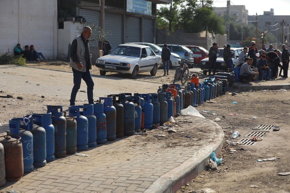 Palestinians sit next to empty cooking gas bottles as they wait to get them refilled at a fuel station in Khan Yunis Palestinians sit next to empty cooking gas bottles as they wait to get them refille ...