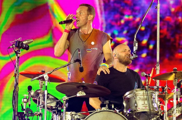 ARCHIV - 12.08.2022, Gro�britannien, London: Chris Martin (l), S�nger von Coldplay, steht neben Will Champion, dem Schlagzeuger der Band, w�hrend der �Music of the Spheres�-Tour auf der B�hne des Wemb ...