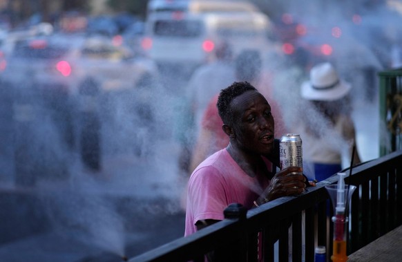 ARCHIV - 14.07.2023, USA, Las Vegas: Ein Mann kühlt sich mit einem Wasserzerstäuber am Las Vegas Strip ab. Der Süden der USA ächzt unter extremer Hitze. Für mindestens 93 Millionen Menschen im Land ge ...