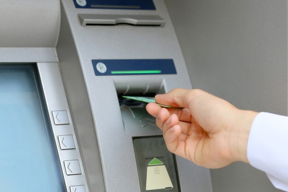 man hand inserting credit card to ATM