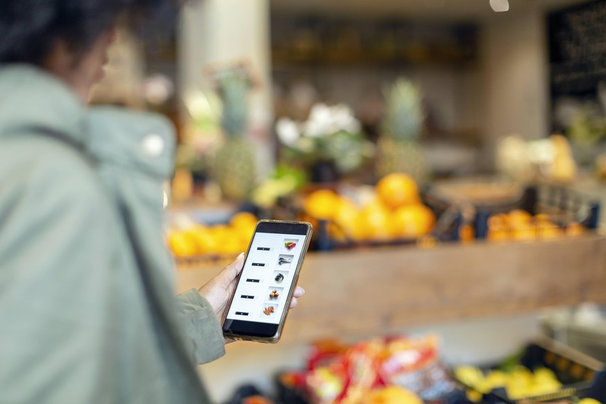 Woman buying groceries through mobile application in supermarket model released Symbolfoto property released EIF00854