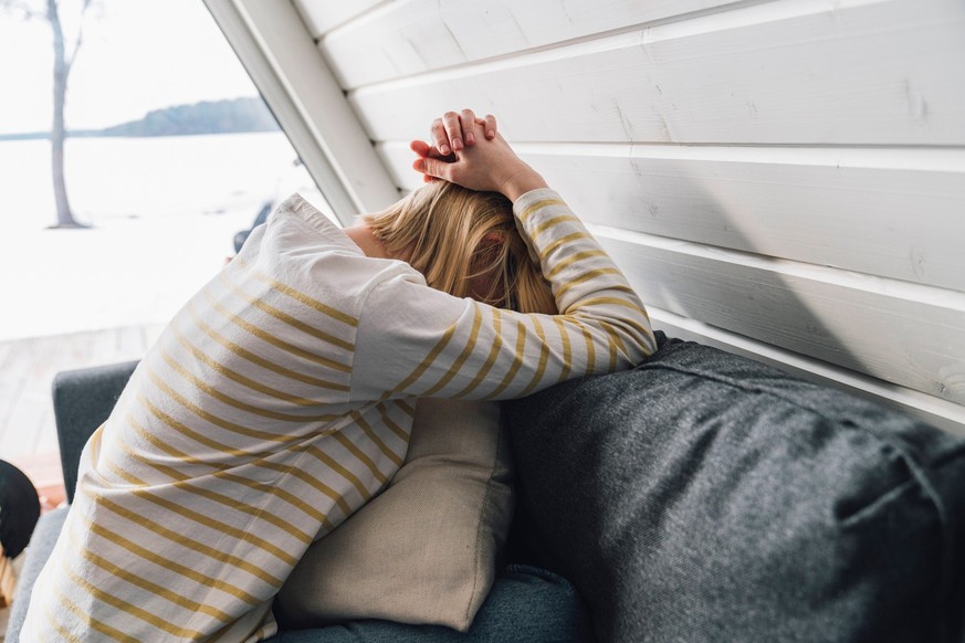 Depressed woman with head in hands sitting on sofa at home model released, Symbolfoto property released, VPIF05942