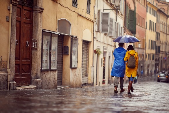 Happy Man and woman in raincoats are walking in the rain