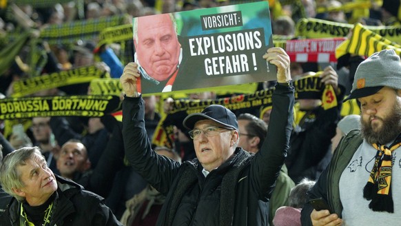 Ein Fan von Borussia Dortmund haelt ein Schild mit dem Portrait von Praesident und Aufsichtsratvorsitzender Uli Hoeness (Muenchen) hoch mit dem Schriftzug Vorsicht: Explosionsgefahr! beim Spiel Boruss ...