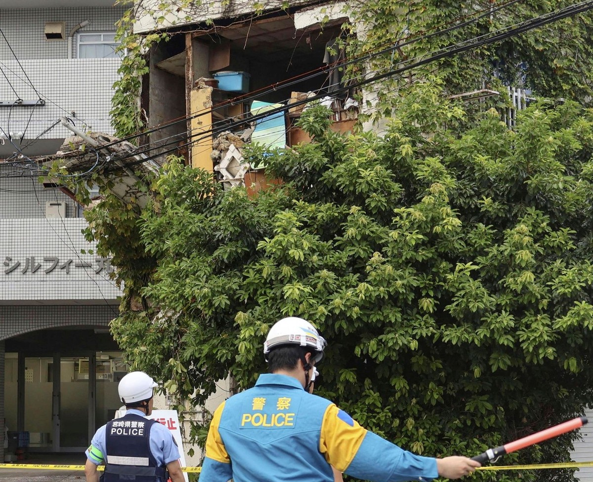 Police stand outside a damaged building following an earthquake in Miyazaki, western Japan, Thursday, Aug. 8, 2024.(Kyodo News via AP)