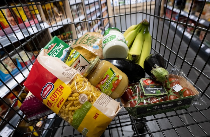 ARCHIV - 18.01.2023, Bayern, Neubiberg: Verschiedene Lebensmittel liegen in einem Supermarkt in einem Einkaufswagen. Die hohe Inflation im Euroraum d