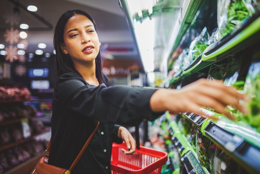 Shot of a young woman shopping for fresh vegetables in a grocery store