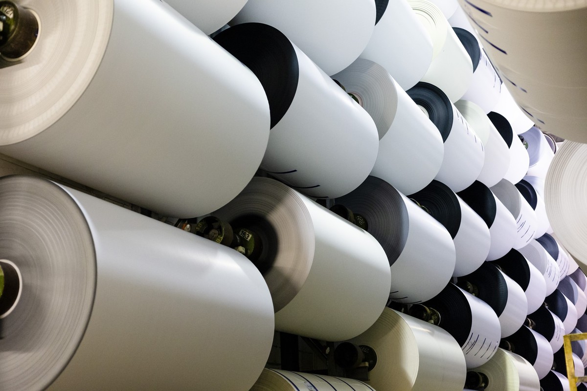 ARCHIV - 20.02.2019, Schleswig-Holstein, Flensburg: Fertig produziertes Papier h�ngt auf Rollen im Lager einer Papierproduktionsfabrik. Die besonders energieintensive Papierindustrie fordert eine R�ck ...