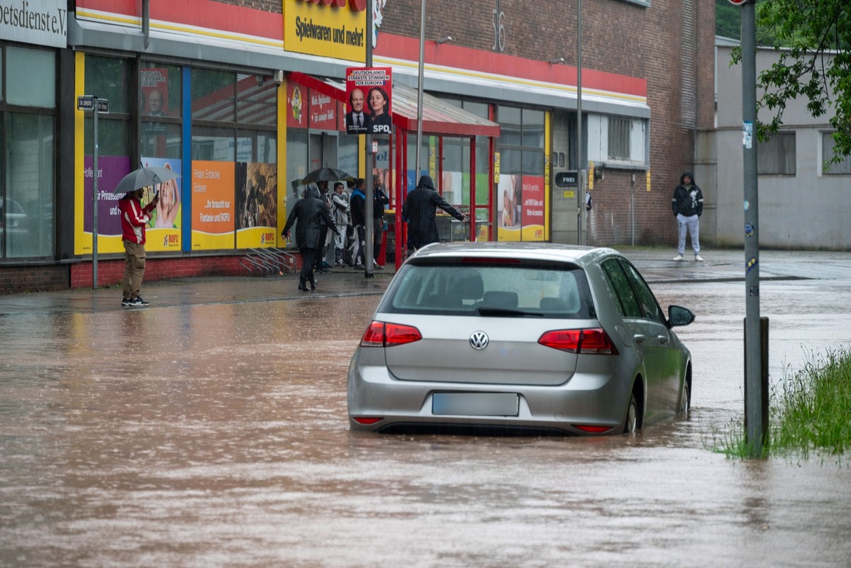 17.05.2024, Saarland, Saarbrücken: Passanten stapfen und fahren durch das Hochwasser in der Fischbachstrasse in Saarbrücken. Nach starken Regenfällen steht diese teilweise unter Wasser. Foto: Harald T ...