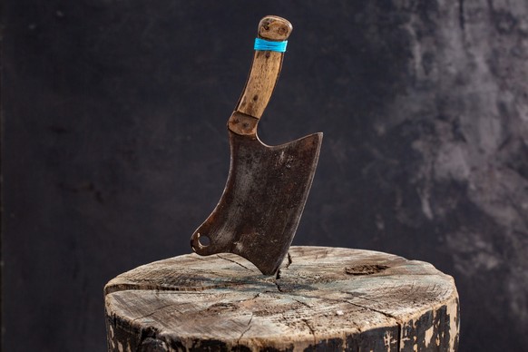 meat axe on a wooden stump or deck on black background
