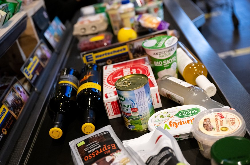 ARCHIV - 18.01.2023, Bayern, Neubiberg: Lebensmittel liegen in einem Supermarkt an der Kasse auf dem Band. (zu dpa