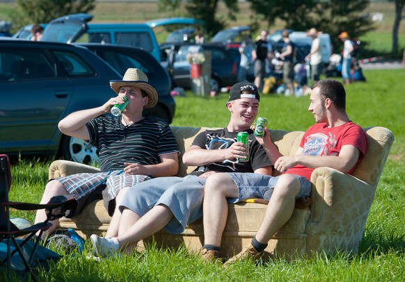 Drei Festivalbesucher sitzen am 18.07.2013 in Nordholz (Niedersachsen) vor Beginn des Musikfestivals &quot;Deichbrand&quot; auf einem mitgebrachten Sofa und warten auf Einlass. Vom 18. bis 21.07.2013  ...